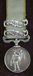 A silver military medal inscribed CRIMEA with two clasps reading INKERMANN and BALAKLAVA, attached to a green and white striped ribbon. The medal depicts a soldier and winged figure.